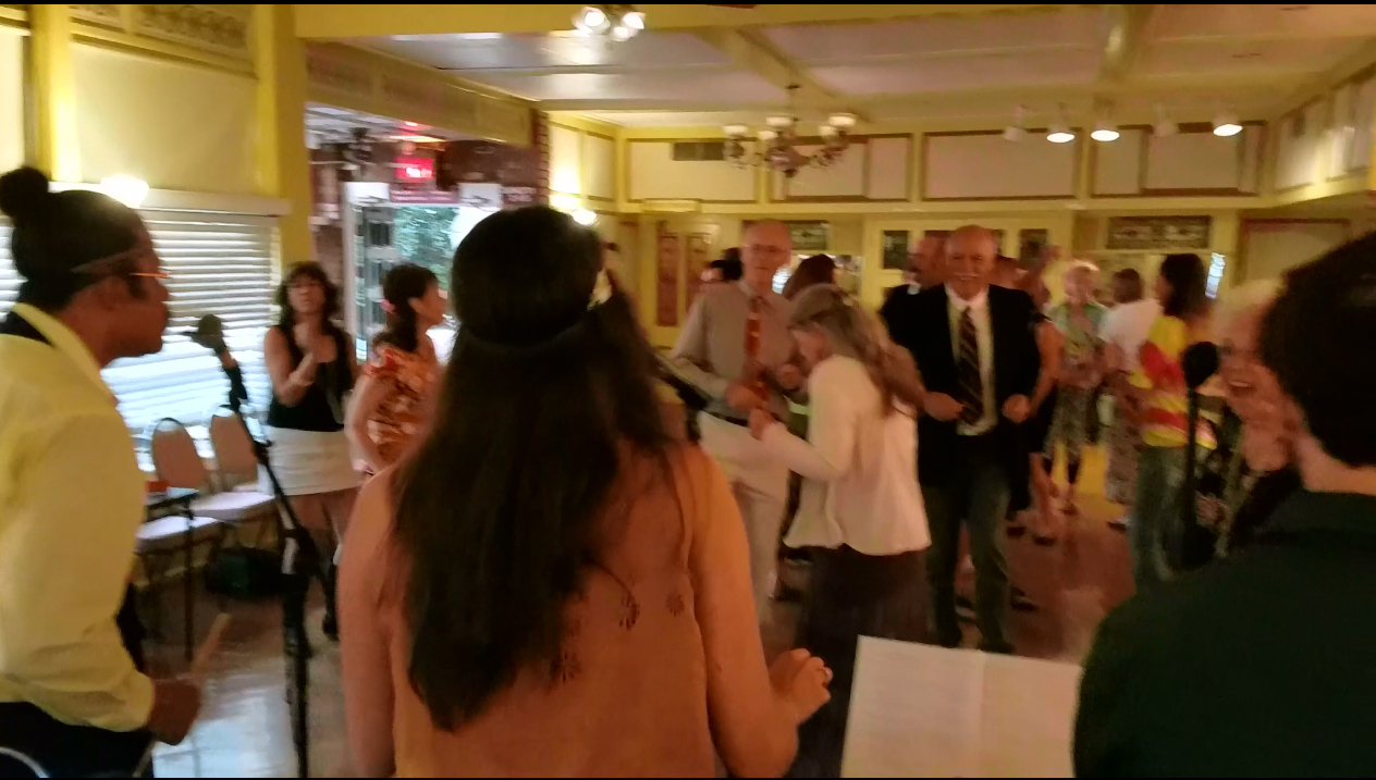 People dancing around the room with singers in frame